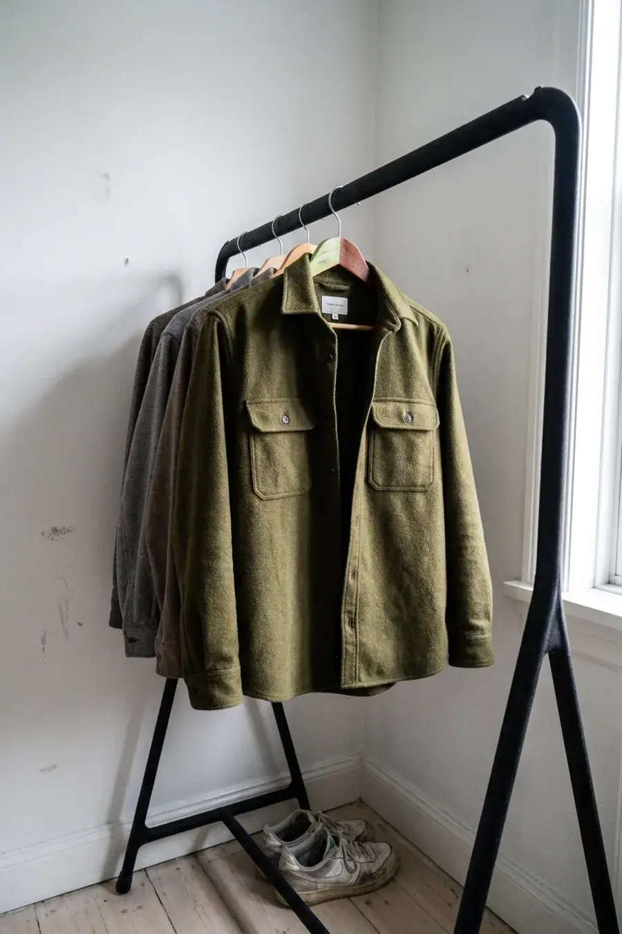 Olivengrøn ulds-overshirt på bøjle på tøjstativ