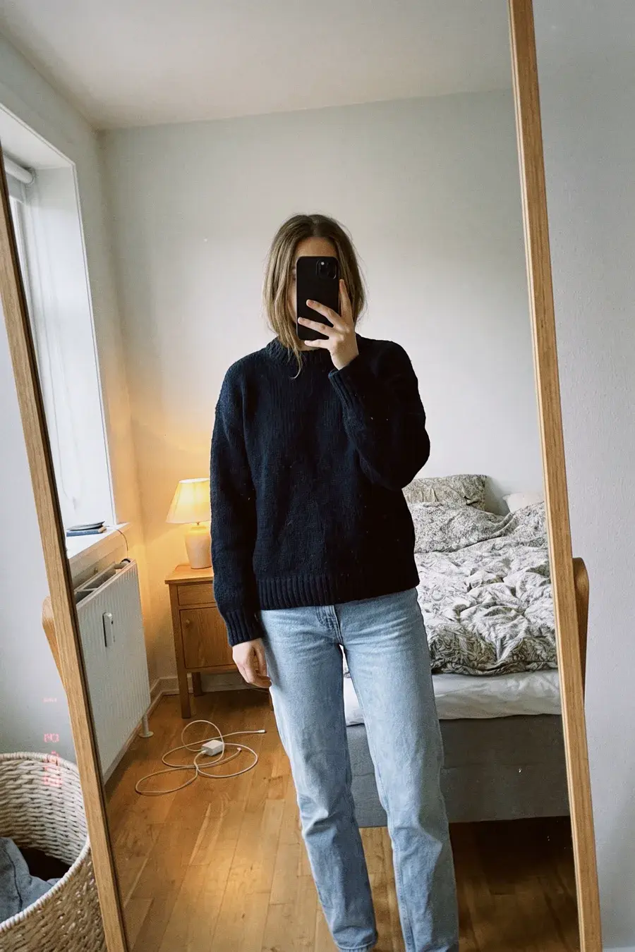 Spejl-selfie i mørkeblå uldstrik og lyse jeans i et lyst soveværelse